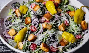 En krämig italiensk sallad till lasagne med gröna blad, tomater, rödlök, oliver, krutonger och gula peppar.