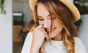 Uśmiechnięta dziewczyna w słomkowym kapeluszu, z lekko falowanymi włosami. Jej stylizacja włosów jest naturalna i swobodna.