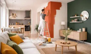 Uomo su scala che inizia a pitturare le pareti di casa con un vivace color arancio.