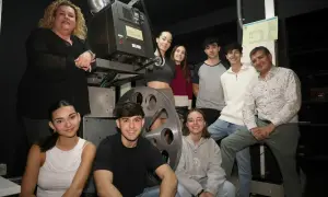 Grupo de jóvenes y adultos posan junto a un proyector antiguo en el cine Cerbuna de Zaragoza.
