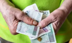 Dłonie trzymają polskie banknoty: 10, 20 i 100 zł. To może być wsparcie z tytułu renta socjalna.
