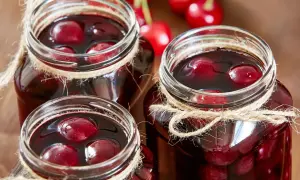 Drei Gläser mit saftigen sauerkirschen einkochen, mit Juteband verziert, bereit für den Winter.