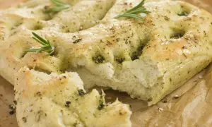 Frisch gebackene italienische Focaccia mit Rosmarin und grobem Salz, auf Backpapier.