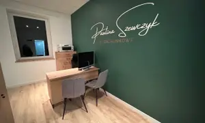 Nowoczesne biuro rachunkowe z zieloną ścianą i napisem "Paulina Szewczyk Biuro Rachunkowe".