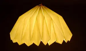 Oświetlony, żółty abażur z papieru, złożony jak origami. Inspiracja, jak zrobić abażur z papieru, dla Twojego wnętrza.