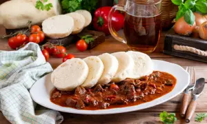 Gulasz z knedlikami, klasyka kuchni czeskiej, podany z piwem i świeżymi pomidorkami.