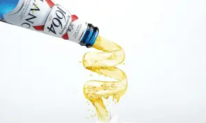 Piwo w niebieskiej butelce Kronenbourg 1664 leje się w fantazyjny sposób, tworząc złoty strumień.