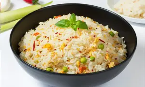 Un bol de riz pilaf aux petits pois, œuf et piment, garni d'une feuille de basilic.