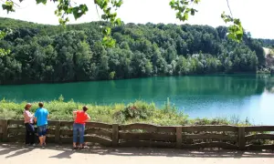 Trzy osoby podziwiają turkusowe jezioro na Wolinie, otoczone gęstym lasem.