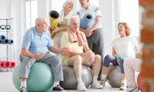 Grupa seniorów po zajęciach rehabilitacja kardiologiczna, odpoczywa na piłkach gimnastycznych, trzymając butelki z wodą.