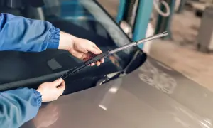 Mains tenant un essuie-glace de voiture, prêt à remplacer ceux qui font du bruit.