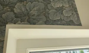 Detaljbild av en vägg med blått blommönster, visar hur tapetserar man runt ett fönster.