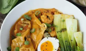 Schüssel mit Ramen, Garnelen, Gyoza, Pak Choi, Ei und Frühlingszwiebeln. Köstliche Ramen-Toppings!