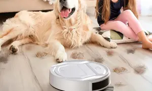 Un robot aspirador limpia el pelo de perro en un hogar mientras una niña acaricia a su mascota.