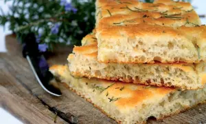 Gestapelte Scheiben knuspriger Focaccia mit Rosmarin auf einem Holzbrett.
