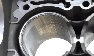 Zużyty cylinder w bloku silnika samochodu, z widocznymi śladami po tłoku.