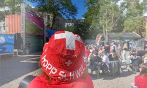 Public viewing Berlin: Ein Fan mit Schweizer Hut jubelt bei einem Fußballspiel.