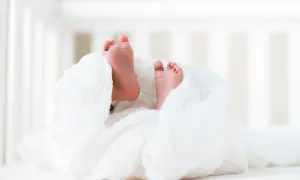 Małe stópki noworodka owinięte w biały kocyk. Czekanie na akt urodzenia to chwila pełna nadziei.