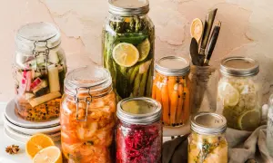 Eingemachtes Gemüse in Gläsern: Karotten, Gurken, Spargel, Kimchi und mehr. Was kann man nicht einkochen? Frische Kräuter und Zitronenscheiben geben Aroma.