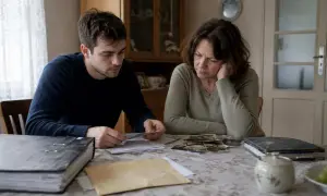 Młody mężczyzna i kobieta przeglądają stare zdjęcia, zastanawiając się, czy wnuki dziedziczą po dziadkach cechy wyglądu i charakteru.