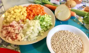 Ingredienti pronti per una saporita minestra d'orzo: orzo perlato, patate, carote, sedano, cipolla e pancetta.
