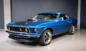 Błękitny Ford Mustang Mach 1 z 1969 roku, z czarną maską i żółtymi światłami, prezentuje się imponująco.