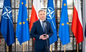 Prezydent Polski przemawia na tle flag NATO i UE. Choć nie wiemy, ile zarabia prezydent Polski, jego pensja jest publicznie dostępna.