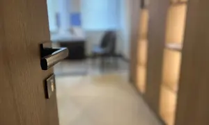 Zbliżenie na klamkę drzwi wewnętrznych, sugerujące jak otworzyć zatrzaśnięte drzwi wewnętrzne. W tle biuro.