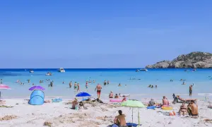 Słoneczna plaża na Majorce, pełna ludzi kąpiących się i opalających. Idealne miejsce na wakacje z dziećmi, oferujące mnóstwo atrakcji.