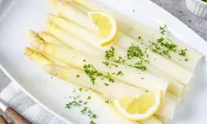 Frischer weißer Spargel, garniert mit Petersilie und Zitronenspalten. Perfekt für die Zubereitung von Spargelgerichten.