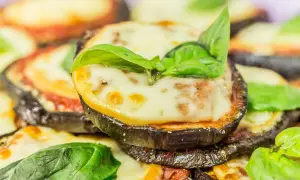 Fette di melanzane cotte al forno, ricoperte di sugo di pomodoro, mozzarella filante e basilico fresco. Un piatto invitante di melanzane alla pizzaiola.