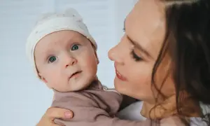 Mama z czułością tuli dziecko. Poradnik: jak nauczyć dziecko ssać pierś po butelce, by karmienie było łatwe i przyjemne.