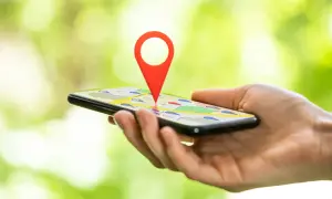 Dłoń trzyma smartfon z mapą i czerwoną pinezką. Dowiedz się, jak zlokalizować telefon przez Google.