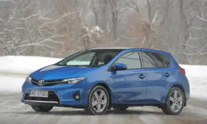Niebieski Toyota Auris na śniegu, z widocznymi przednimi żarówkami.