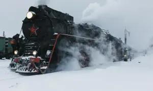 Parowóz z czerwoną gwiazdą, gotowy do podróży przez śnieżny krajobraz. To obraz, który przywodzi na myśl legendarną kolej transsyberyjską.