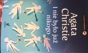 Okładka książki Agaty Christie "I nie było już nikogo". Papierowe ludziki z czerwonymi kropkami, jakby trafione.