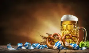Boccale di birra dorata, pretzel e nastri bavaresi evocano la storia dell'Oktoberfest.