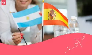 Persona sonriente sostiene banderas de Argentina y España. ¡Una oportunidad para un working holiday!
