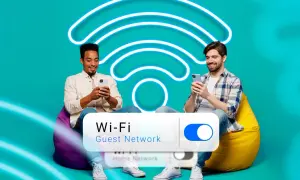 Deux hommes souriants sur des poufs, utilisant leurs téléphones. Un grand symbole Wi-Fi lumineux et un interrupteur "Wi-Fi Guest Network" sont visibles.