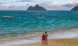 Para młoda na plaży, podziwiająca łodzie na turkusowym morzu. Idealne miejsce na podróż poślubną.