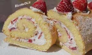 Un delizioso rotolo panna e fragole, soffice pan di Spagna arrotolato con crema e pezzetti di fragole fresche, decorato con zucchero a velo e fragole intere.