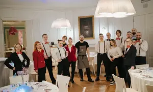 Zespół kelnerów w eleganckich strojach, z muszkami w stylu pellegrino, gotowy do obsługi przyjęcia.
