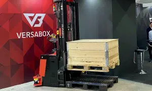 AGV robot VersaBox podnosi drewnianą skrzynię na palecie.