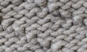 Nahaufnahme einer dicken, grauen Stricktextur. Die einzelnen Fäden sind flauschig und weich, ideal für das Mohair waschen.