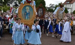 Procesja niesie ozdobne feretrony z obrazami Matki Bożej i Świętej Rodziny. Tłum ludzi towarzyszy niesionym feretronom.