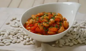 Schmackhafte weiße Bohnen in Tomatensoße, garniert mit Schnittlauch. Die Frage "wie lange bohnen kochen" wird hier visuell beantwortet: Sie sind perfekt gegart und servierfertig.