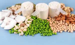Białko z grochu, kokos, migdały, ciecierzyca i pistacje. Trzy miarki proszku proteinowego na niebieskim tle.
