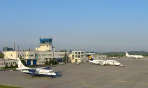 Lotnisko Katowice z wieżą kontroli lotów i samolotami na płycie. Które lotnisko większe Kraków czy Katowice?