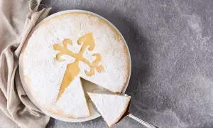 Una fetta di torta di Santiago, cosparsa di zucchero a velo, con la tipica croce incisa.