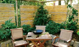 Ausgefallener Sichtschutz Garten selber machen: Bambusmatten und Holzmöbel schaffen eine gemütliche Ecke.